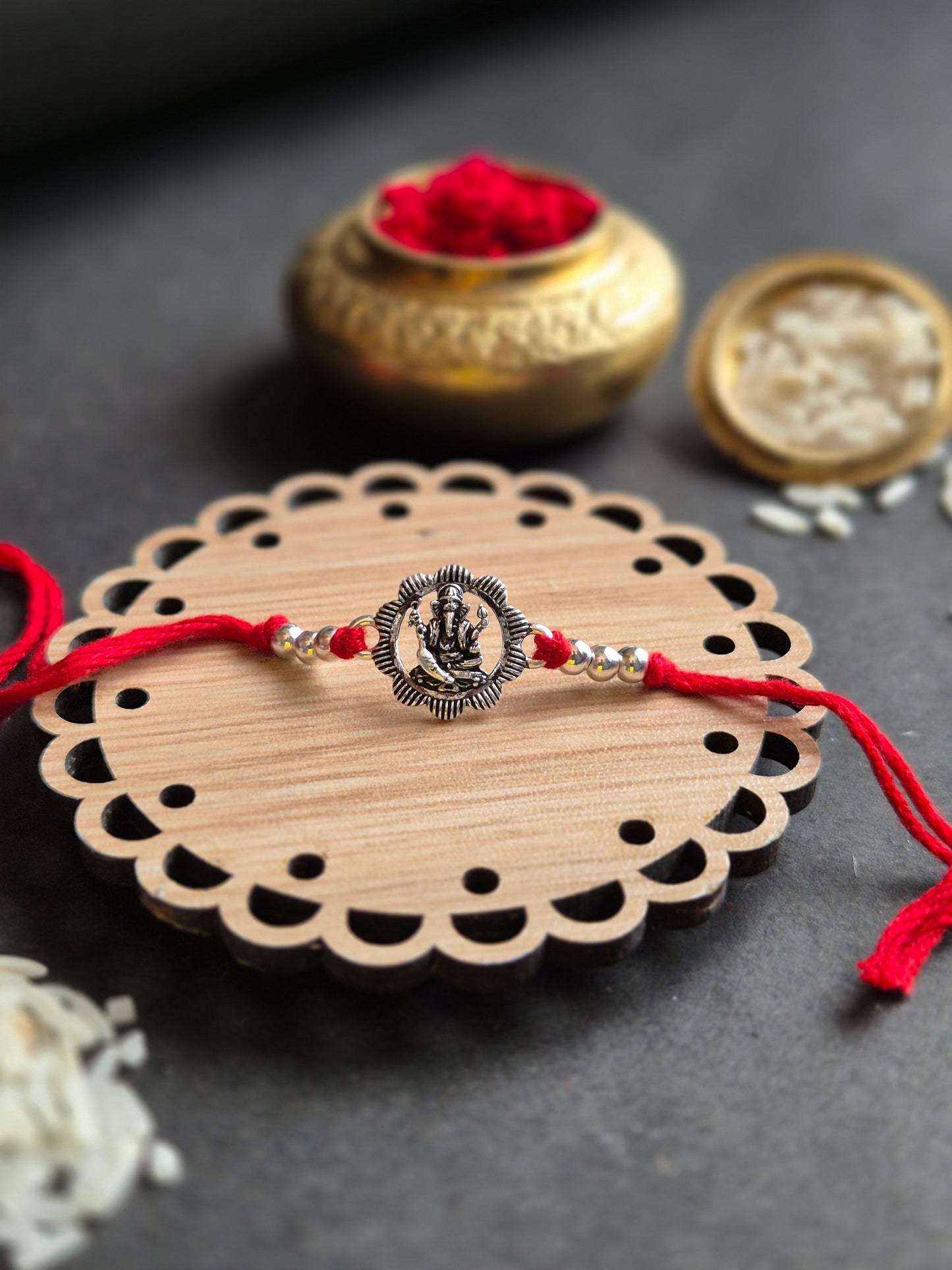 Divine Ganesha sterling silver rakhi with intricate pendant on a decorative coaster, symbolizing blessings and protection.