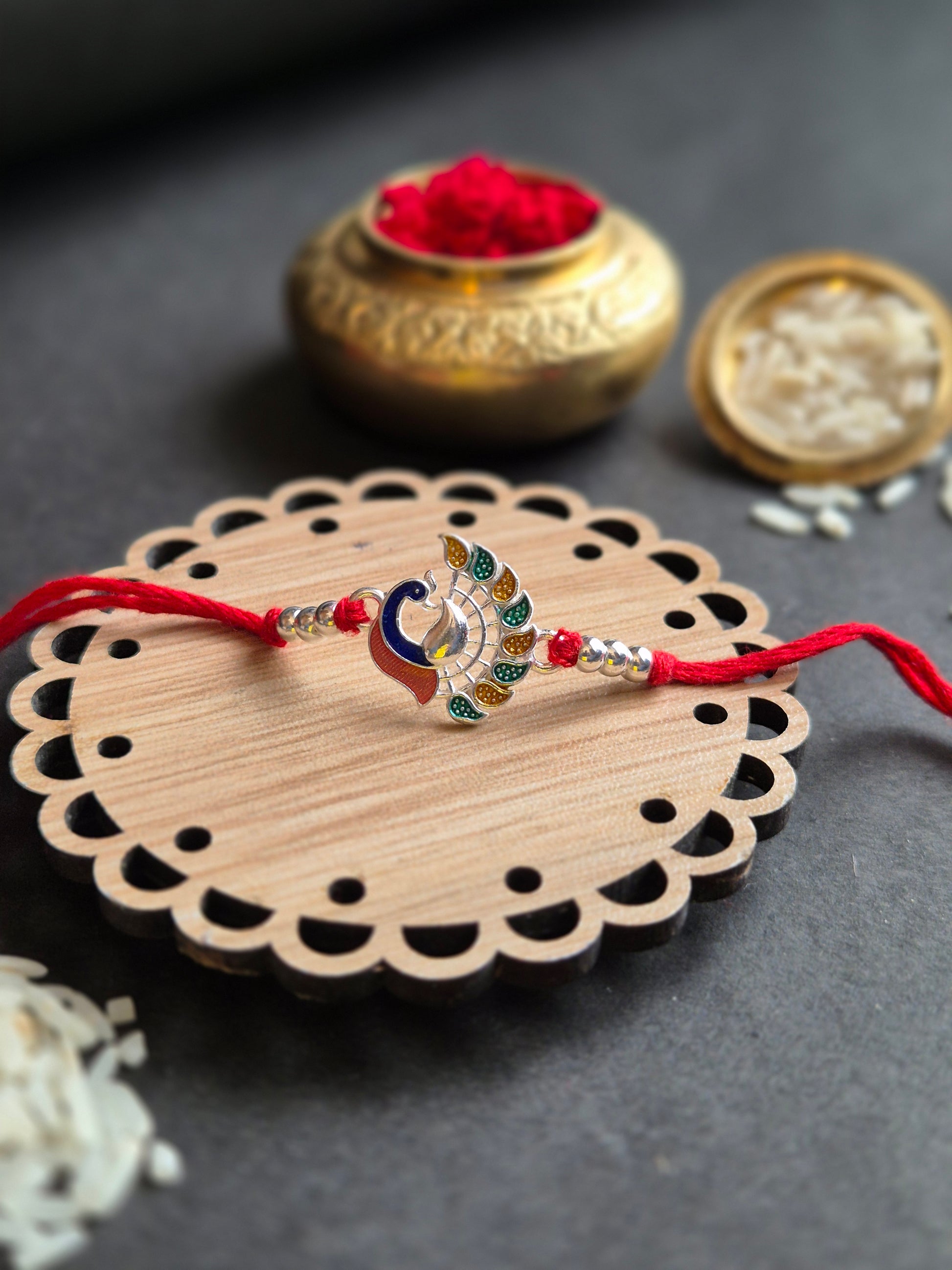 Majestic Peacock Sterling Silver Rakhi on decorative wooden plate, symbolizing beauty and grace for Raksha Bandhan.