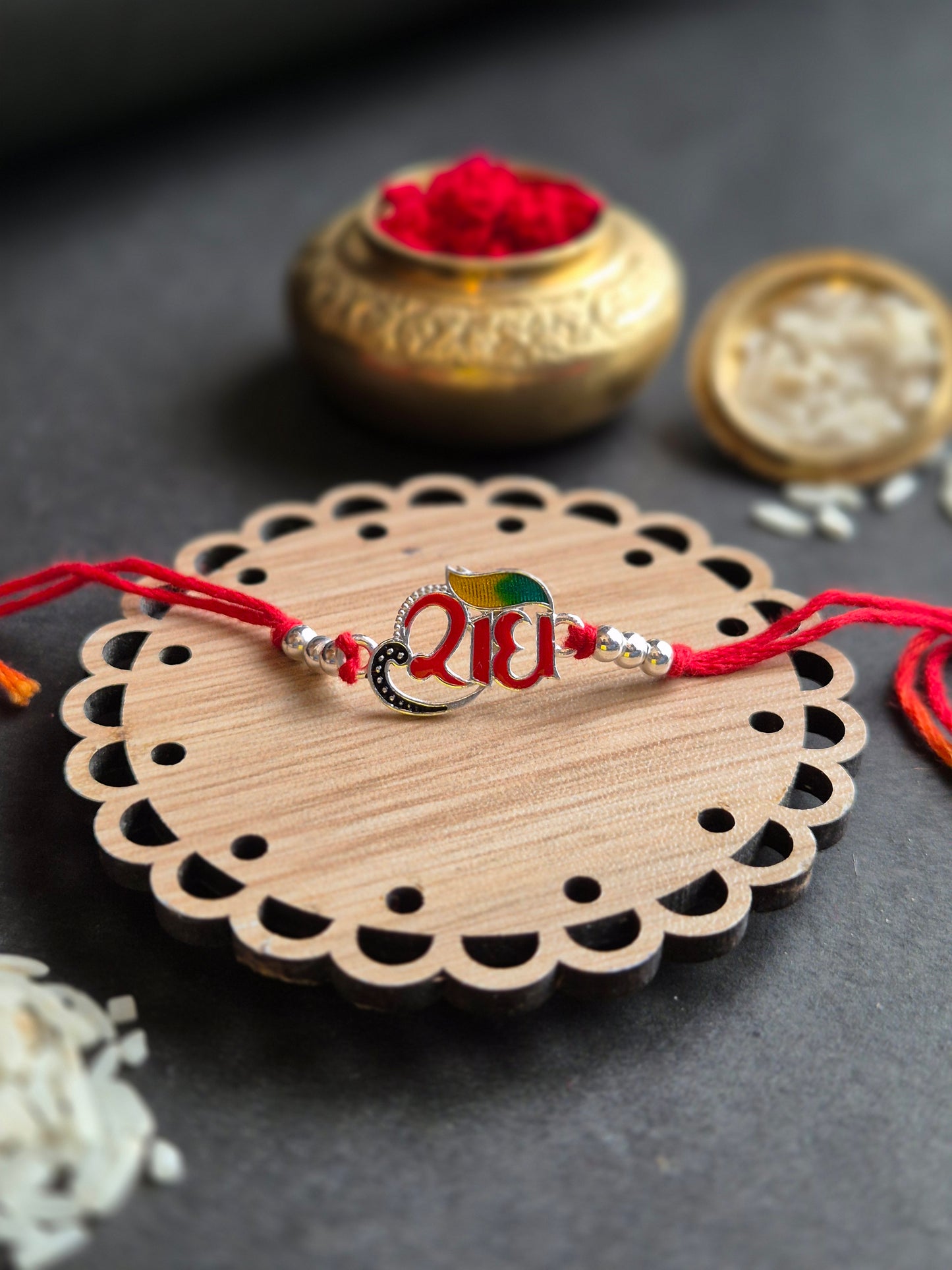 Divine Radha sterling silver rakhi with colorful peacock motif on a decorative wooden plate.