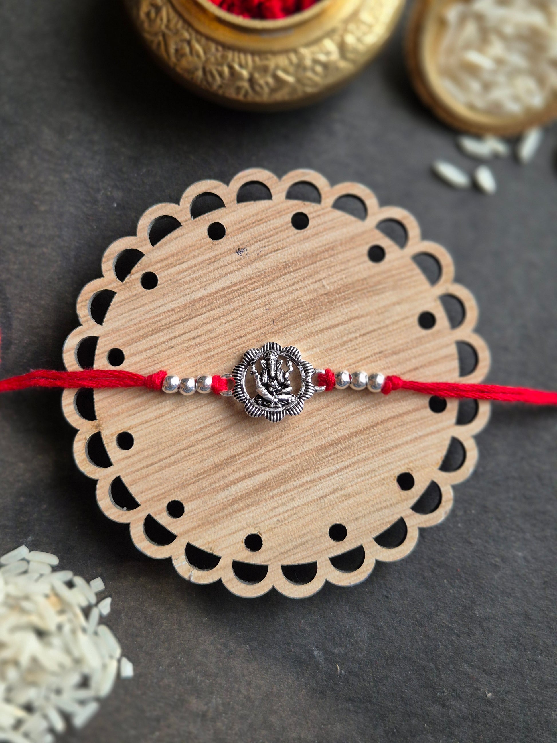 Divine Ganesha sterling silver rakhi, handmade with love, featuring Ganesha pendant and beads on decorative round base.