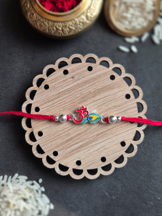 Hand-painted Om symbol rakhi on wooden coaster, decorated with silver beads and red thread for Raksha Bandhan.