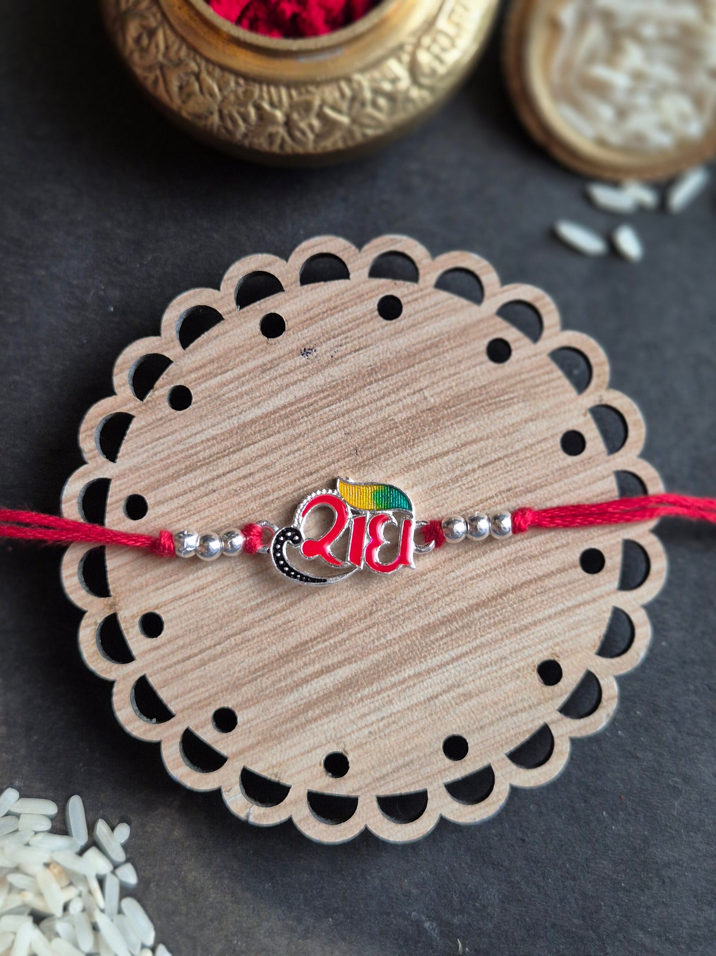 Divine Radha sterling silver rakhi with vibrant peacock feather and Hindi script 'राधा' on handcrafted base.