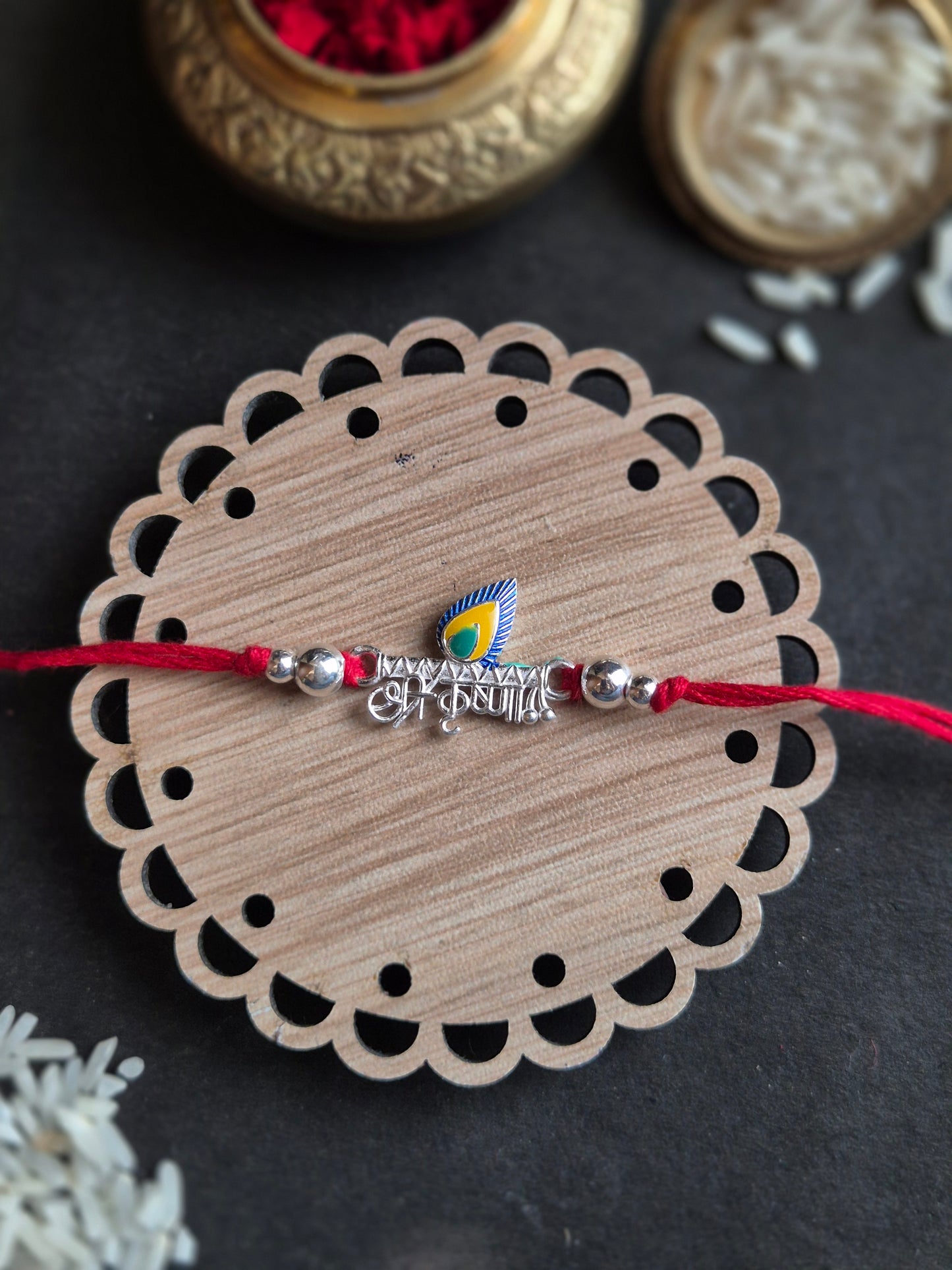 Divine Kanha Sterling Silver Rakhi with elegant Hindi script on a decorative round base, symbolizing love and devotion.