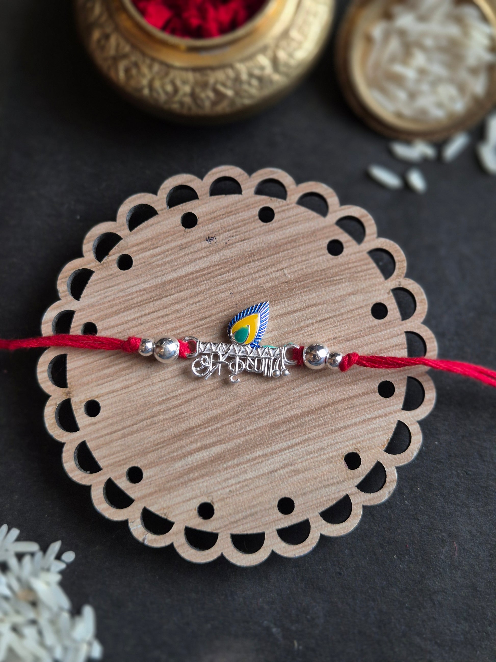 Divine Kanha Sterling Silver Rakhi with elegant Hindi script on a decorative round base, symbolizing love and devotion.